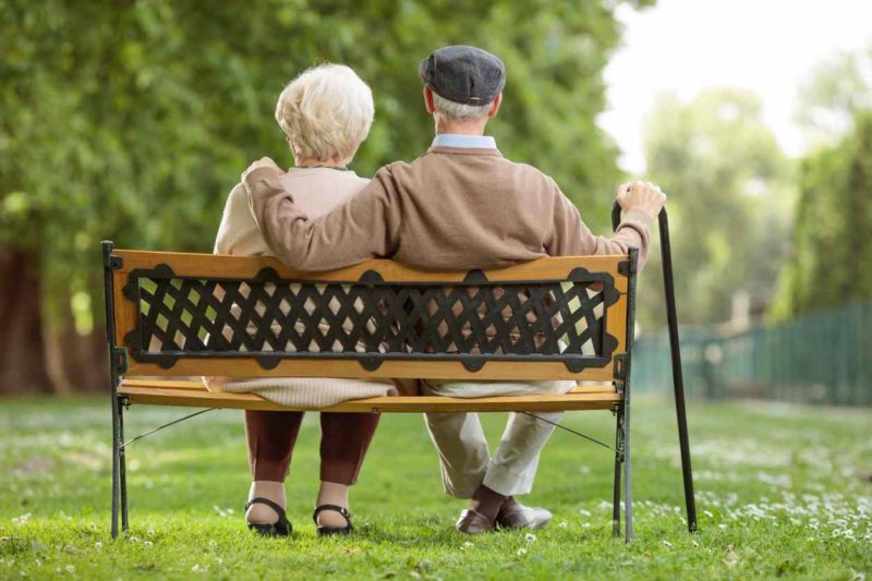 Senior couple sitting on a wooden bench in the park